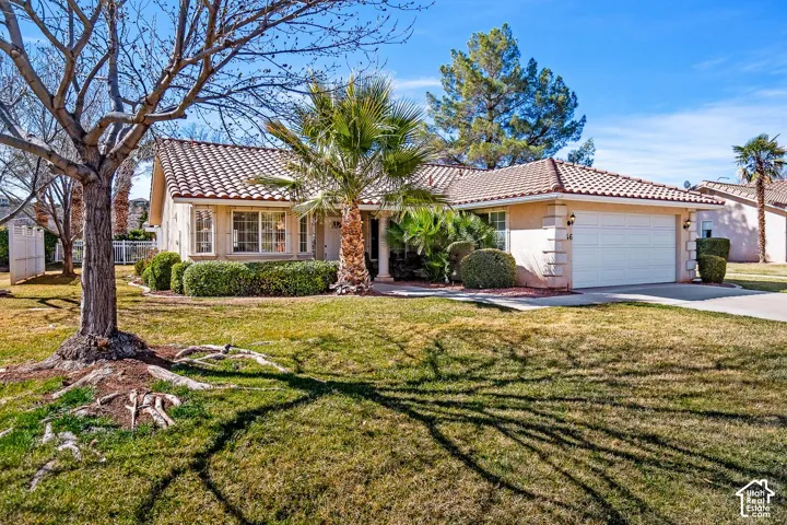 Single-story stucco exterior featuring a tile roof, an attached two-car garage, and mature landscaping