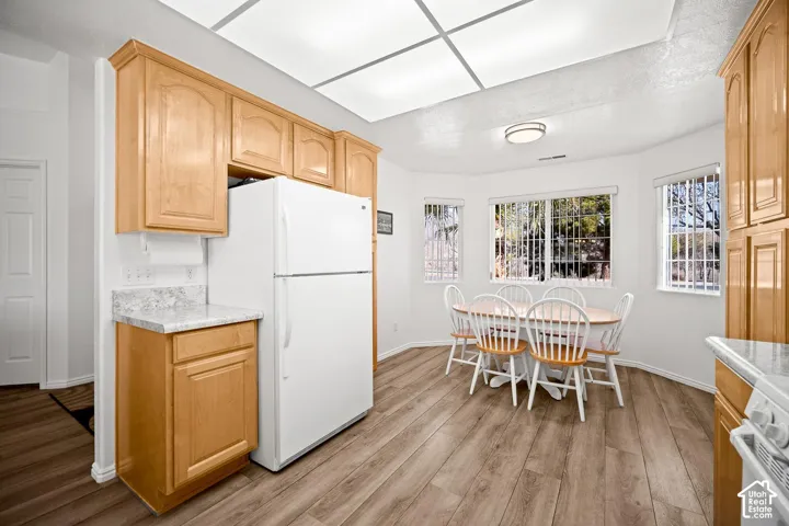 Kitchen featuring natural wood cabinetry, stone-patterned laminate countertops, wood-finish flooring, and a recessed ceiling panel