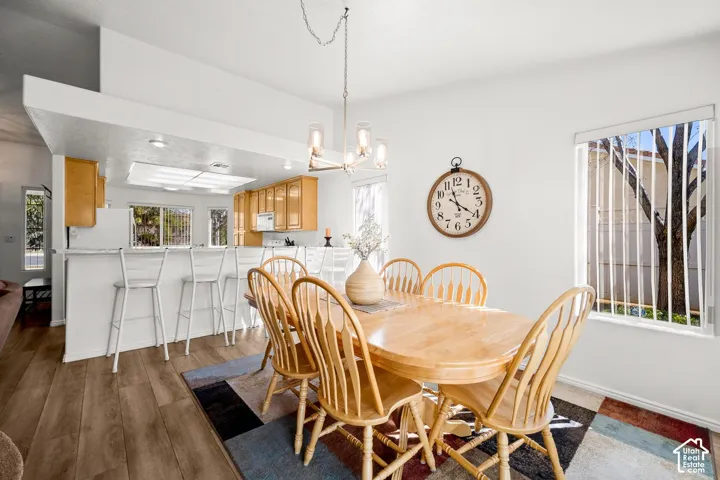 Dining area featuring wood-finish flooring, a multi-light chandelier, and a kitchen breakfast bar with built-in cabinetry