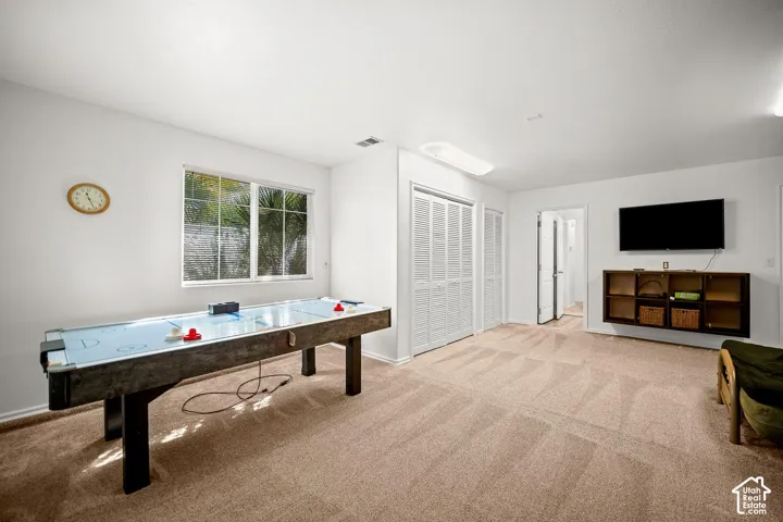 Neutral-toned carpeted flooring, white bi-fold closet doors, wall-mounted display shelving, large window with exterior visibility, and overhead flush-mount lighting