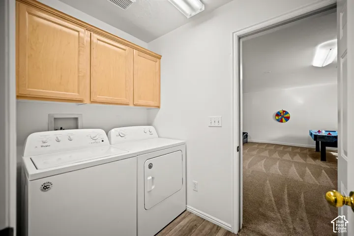 Laundry room featuring upper wood-finish cabinetry, fluorescent lighting, and wood-finish flooring