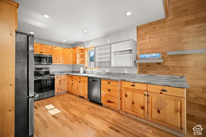 Kitchen featuring natural wood cabinetry, stone-finish countertops, wood-finish flooring, recessed lighting, and horizontal wood wall paneling