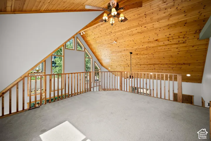 Vaulted ceiling with natural wood-plank paneling, multi-level architectural windows, and custom wooden handrail balustrade