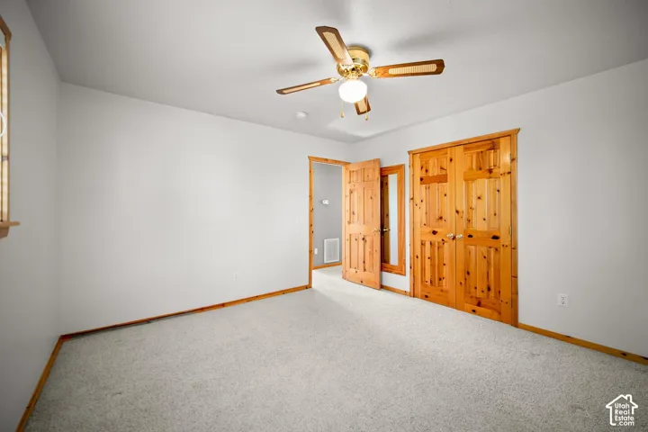 Neutral wall coloring with wood-trim finish, wall-to-wall carpeting, ceiling fan with light fixture, and wooden interior doors