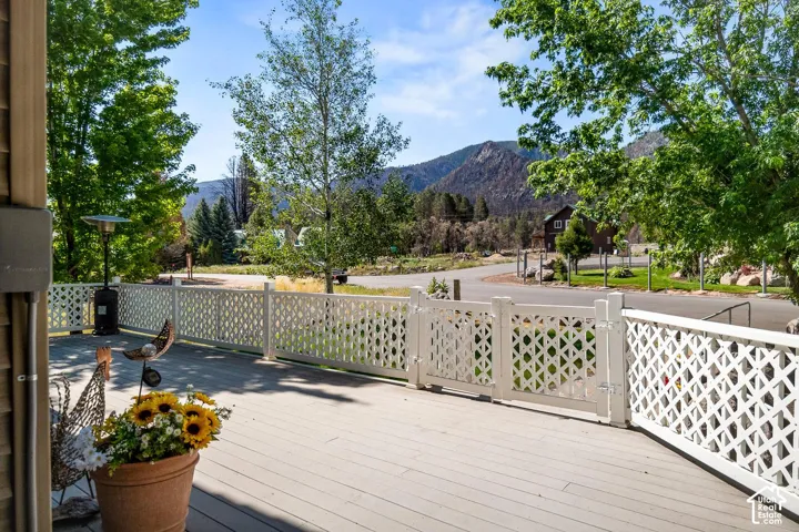 Composite deck featuring white lattice perimeter fencing, a locking gate, and mountain terrain backdrop