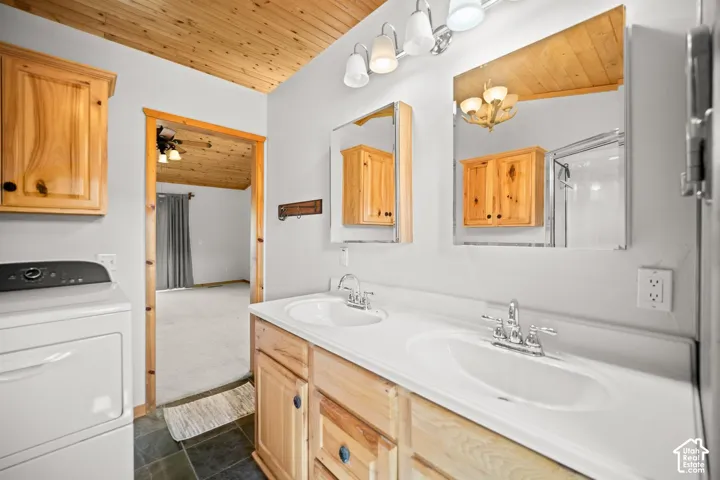 Dual-sink vanity with natural wood cabinetry and countertop, wood-plank ceiling, and four-light vanity fixture