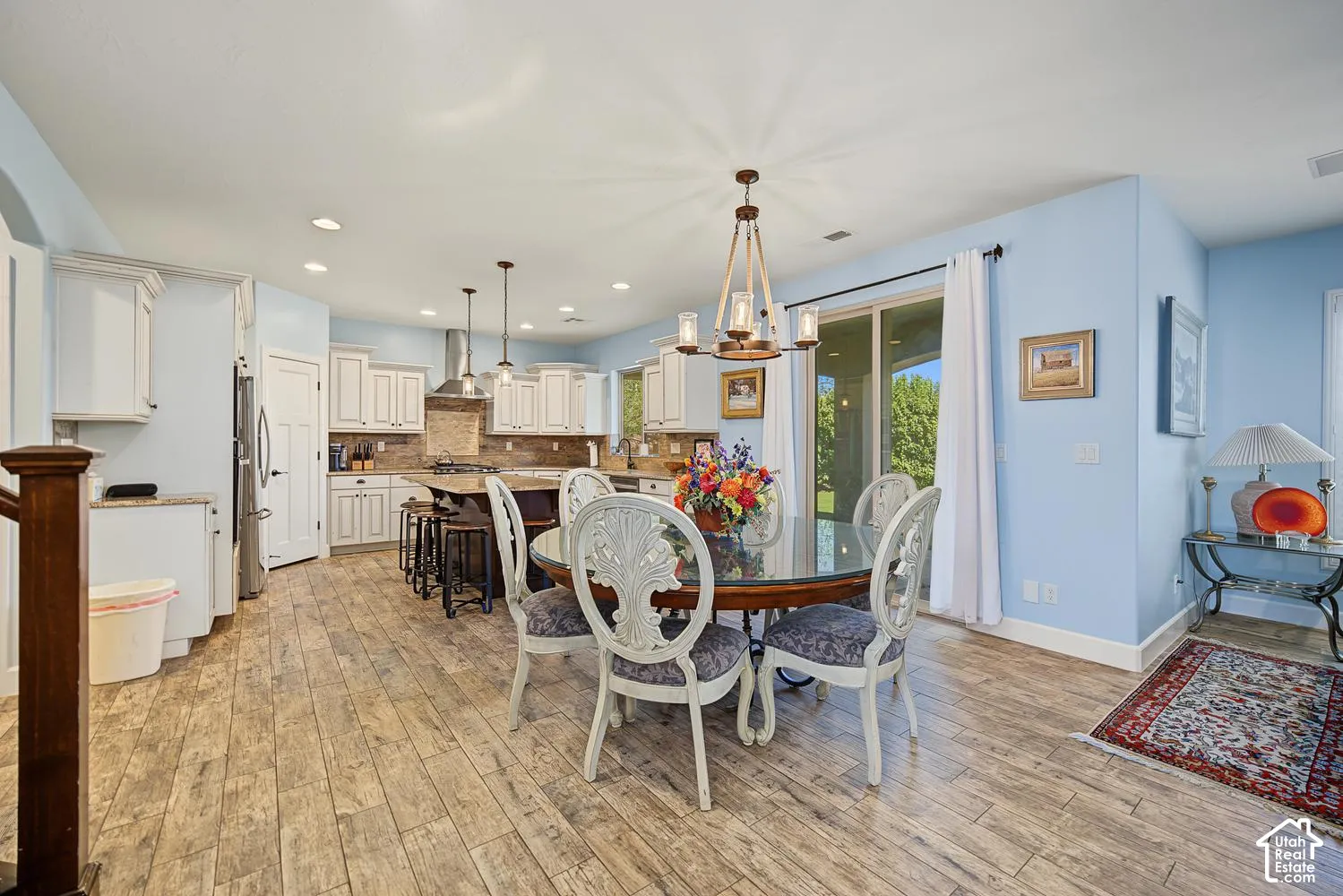 Kitchen featuring a center island, white cabinetry, stone-finish countertops, wood-finish flooring, and a multi-light chandelier