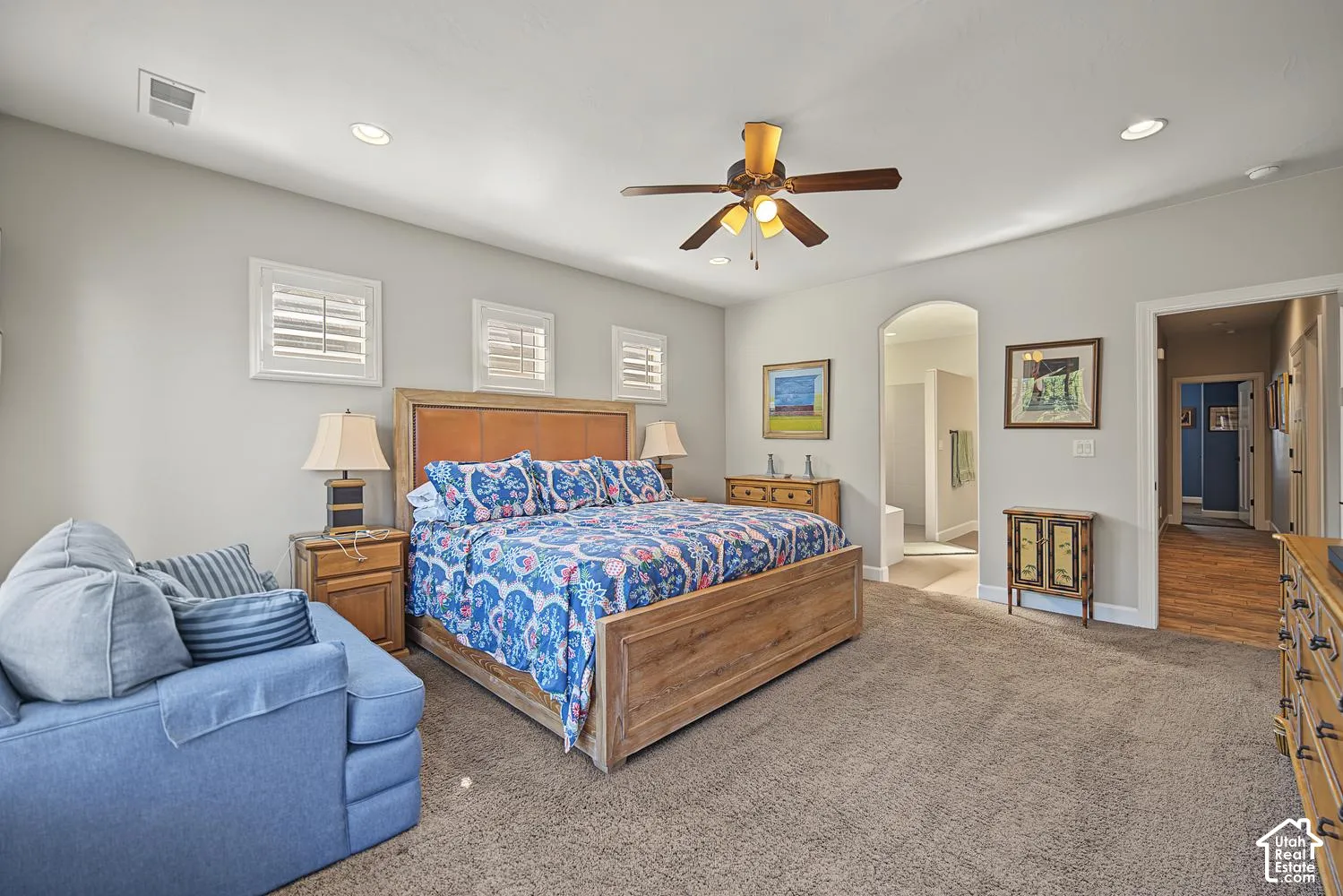 Neutral-toned walls, arched entryway, recessed lighting, ceiling fan with integrated light fixture, and square-pane windows with shutter treatments