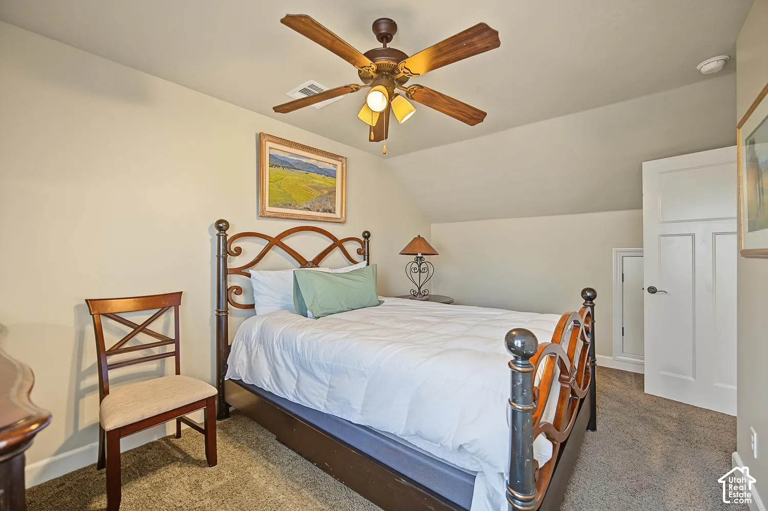 Neutral-toned room featuring a vaulted ceiling, carpeting, a ceiling fan with integrated lighting, and a multi-panel interior door