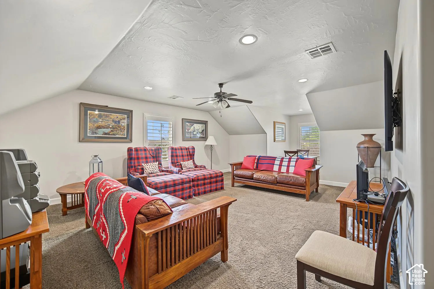 Vaulted ceilings, neutral wall tones, recessed lighting, ceiling fan, and multi-pane windows with plantation-style shutters