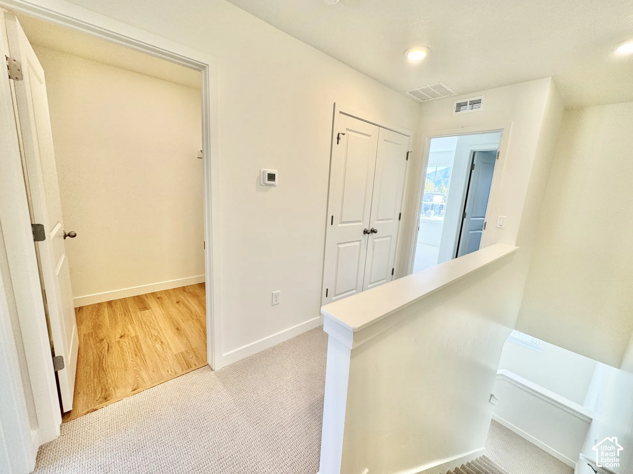Hallway featuring wood-finish flooring, neutral carpeting, recessed ceiling lighting, and two-panel interior doors