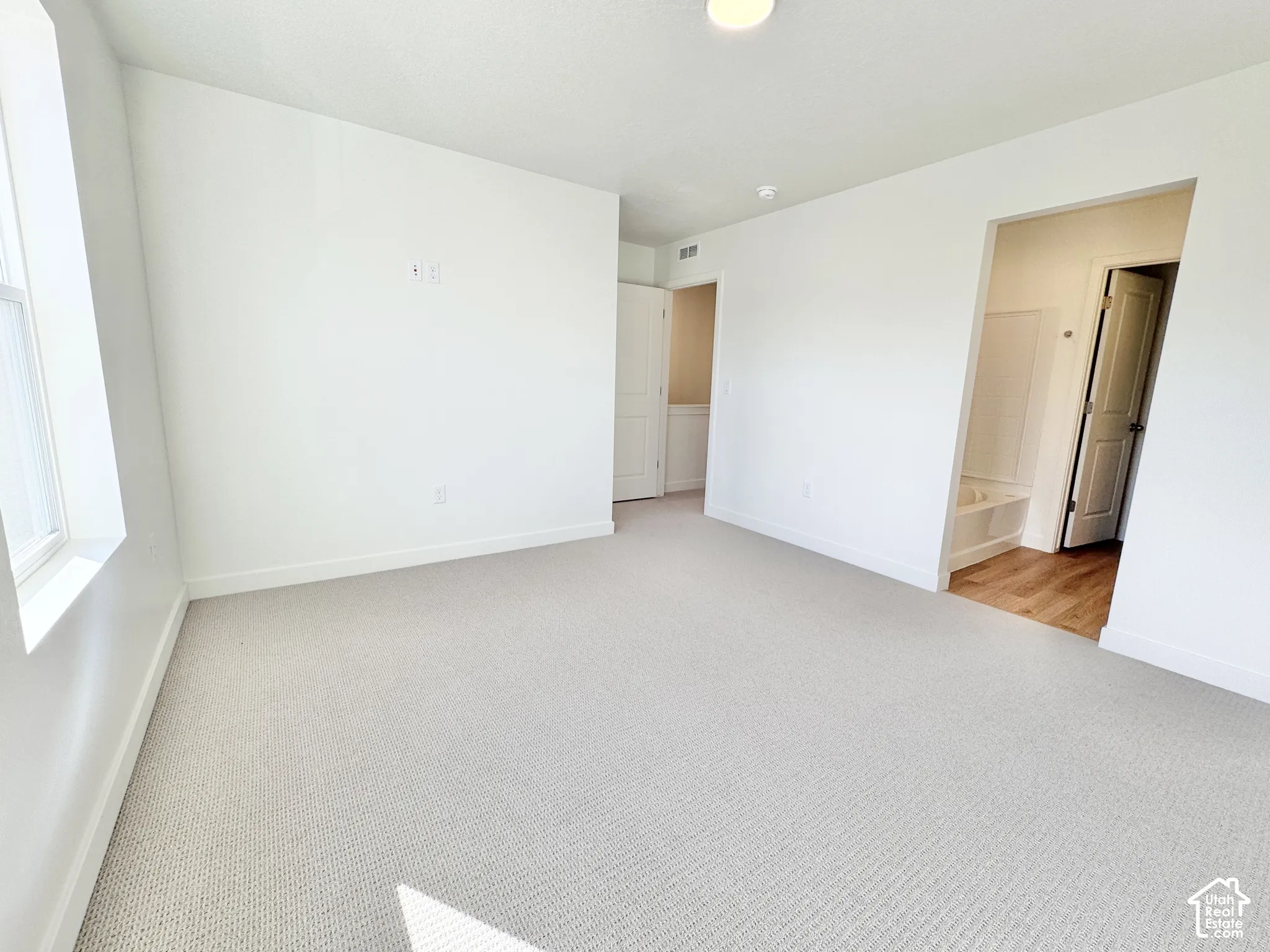 Neutral-toned carpeting, crisp white walls, recessed lighting, and interior doors