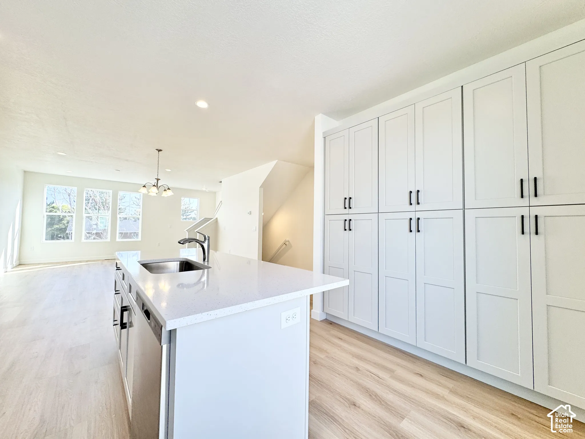 Kitchen island featuring a stone-surface countertop, stainless steel undermount sink, and integrated dishwasher