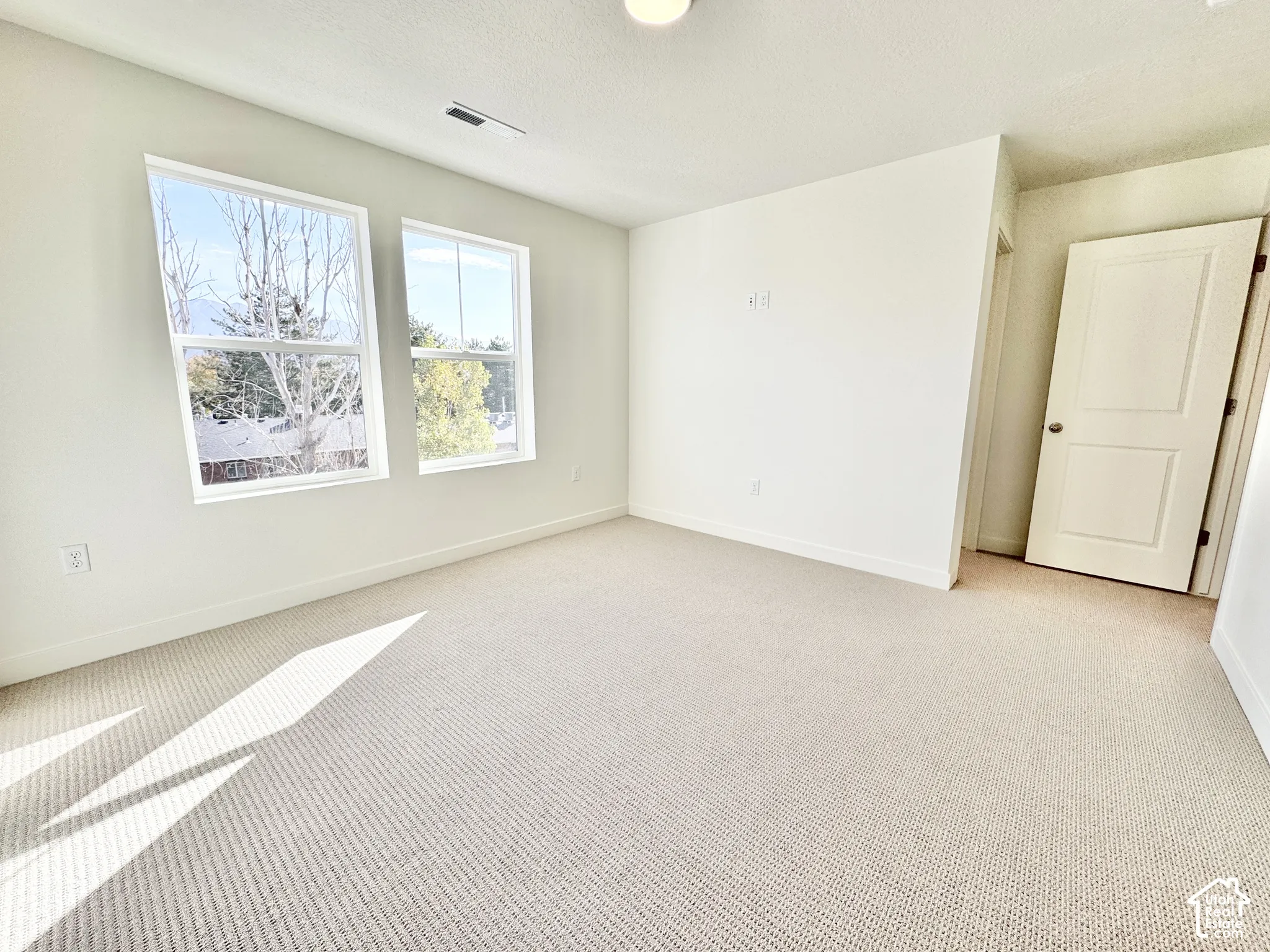 Neutral-toned wall-to-wall carpeting, dual paned windows, two-panel interior door, and neutral wall palette