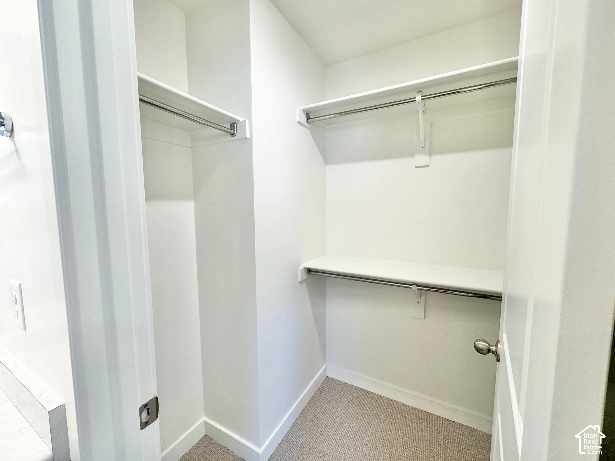 Walk-in storage space featuring custom shelving and dual metal clothing rods