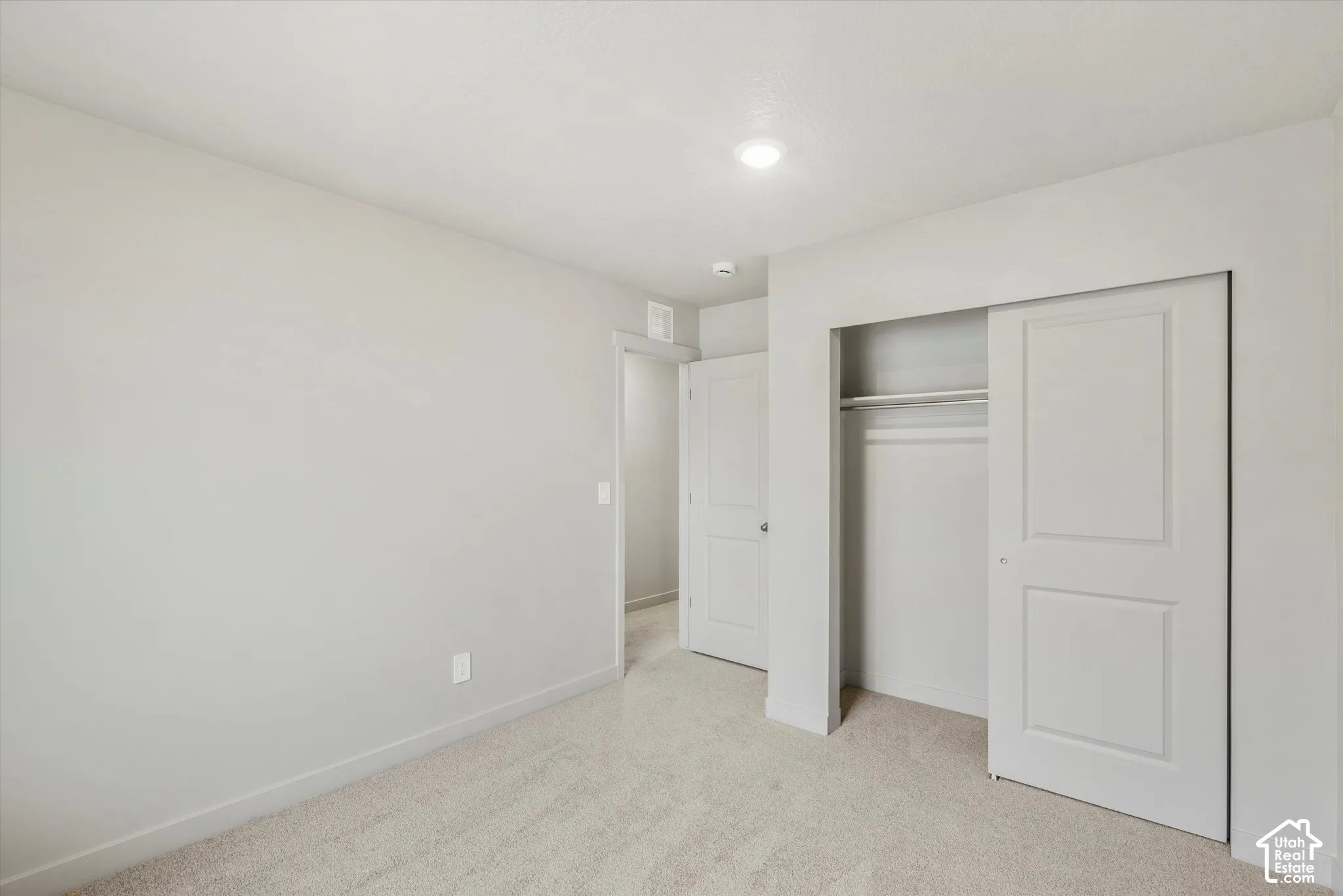 Neutral-toned carpeted flooring, recessed ceiling lighting, and a closet with a two-panel sliding door