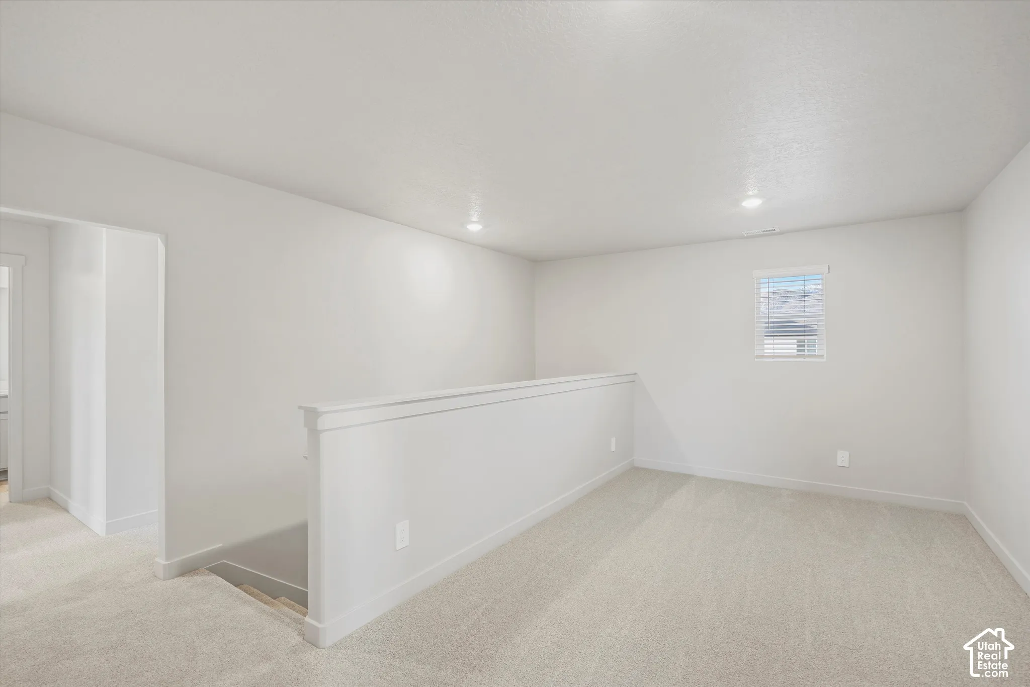 Neutral-toned carpeting, recessed ceiling lighting, and a painted half-wall with a cap rail
