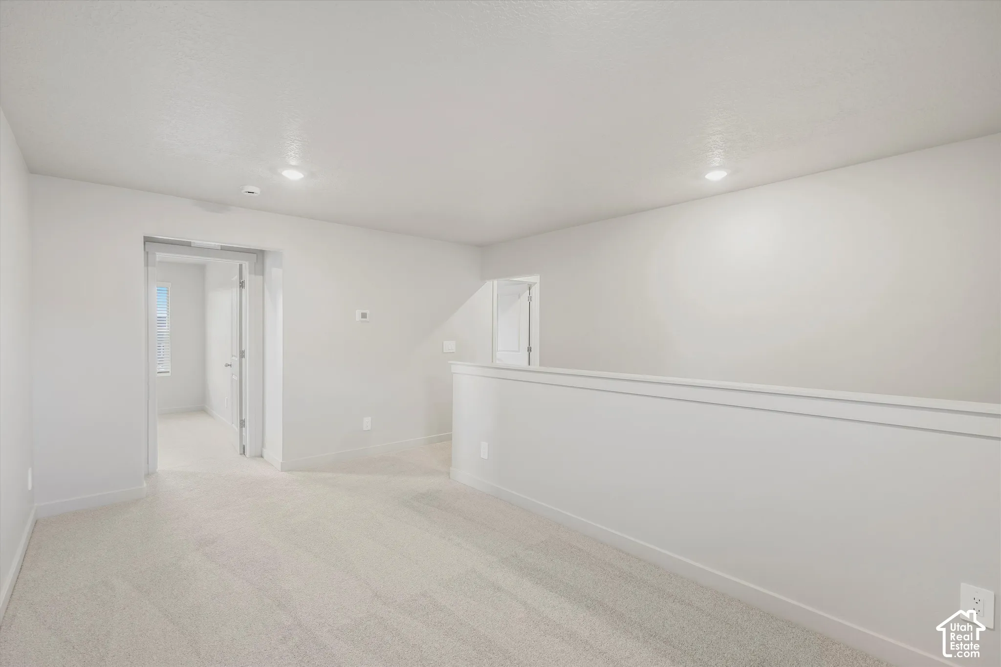 Neutral-toned interior space featuring wall-to-wall carpeting, recessed ceiling lighting, and a partial height wall partition