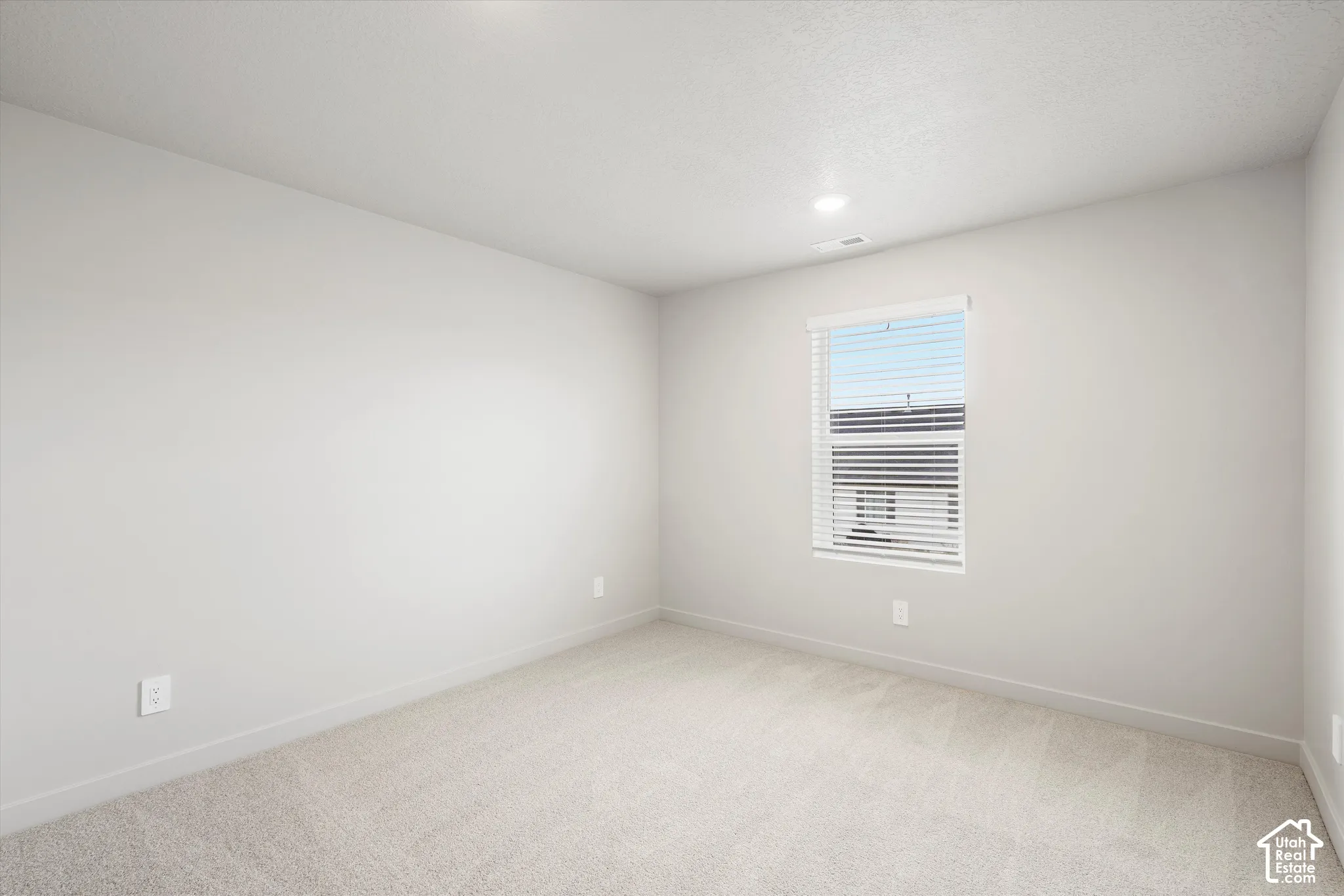 Neutral wall paint, plush carpeting, single-hung window with horizontal blinds, and recessed lighting