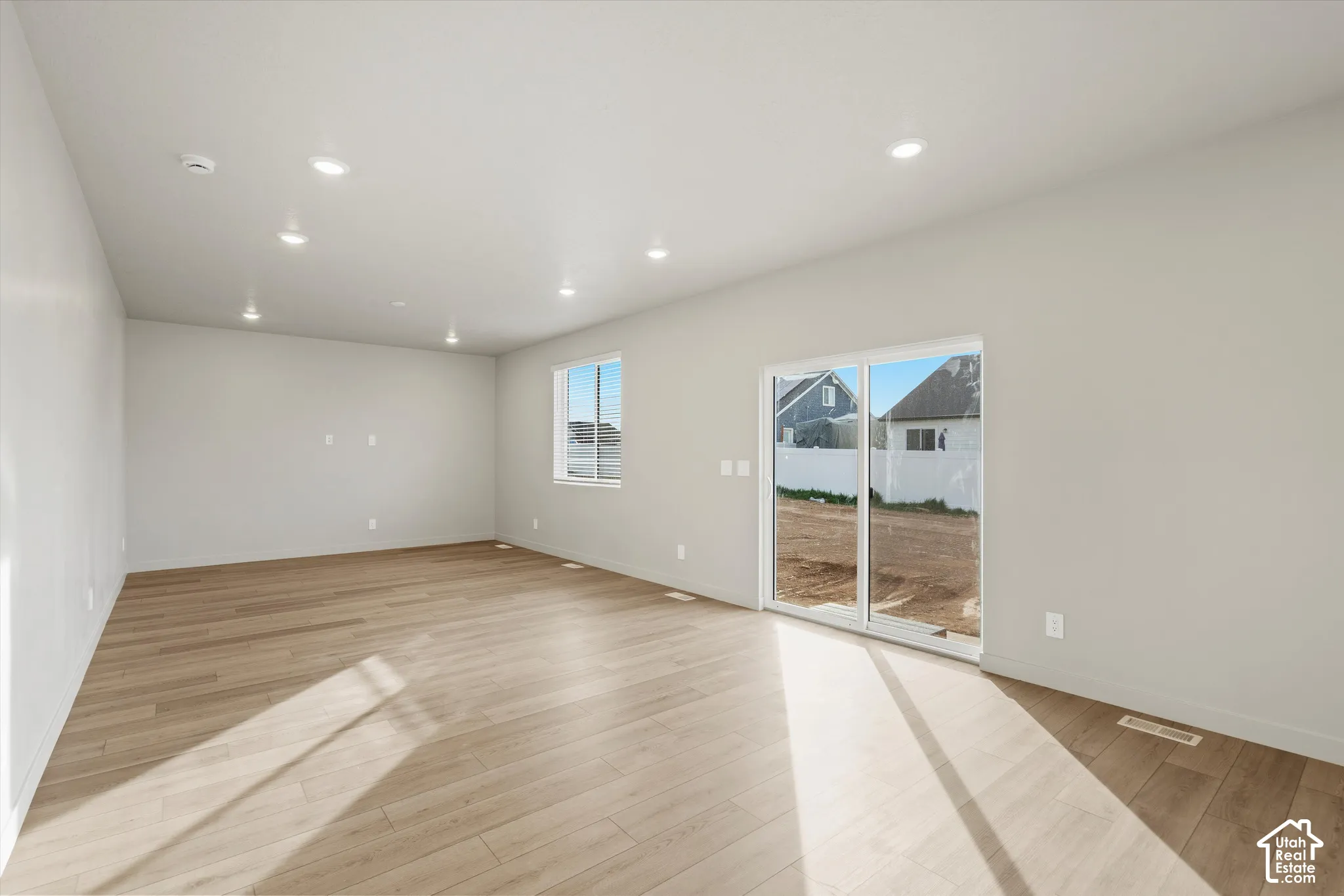 Neutral-toned interior featuring wood-finish flooring, recessed lighting, and a sliding glass door
