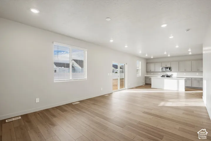 Open-concept interior featuring wood-finish flooring, recessed lighting, a kitchen with cabinetry, and glass sliding doors