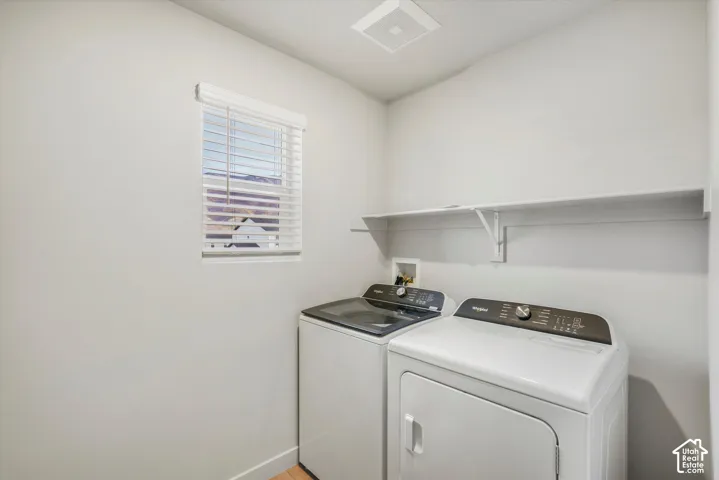 Laundry area featuring a window with horizontal blinds, neutral wall paint, and a built-in wall-mounted shelf