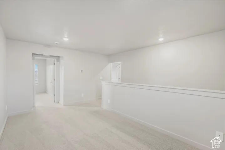Neutral-toned interior space featuring wall-to-wall carpeting, recessed ceiling lighting, and a partial height wall partition