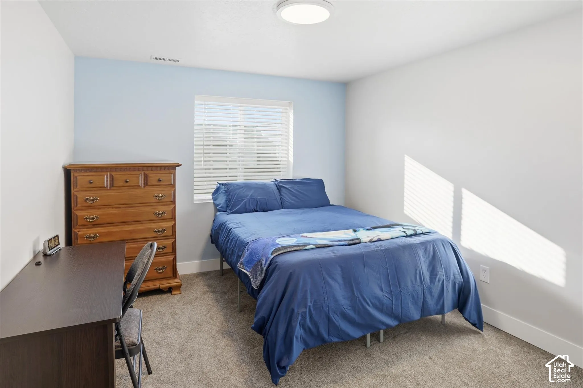 Neutral wall tones, wall-to-wall carpeting, and a dual-pane window with installed horizontal blinds