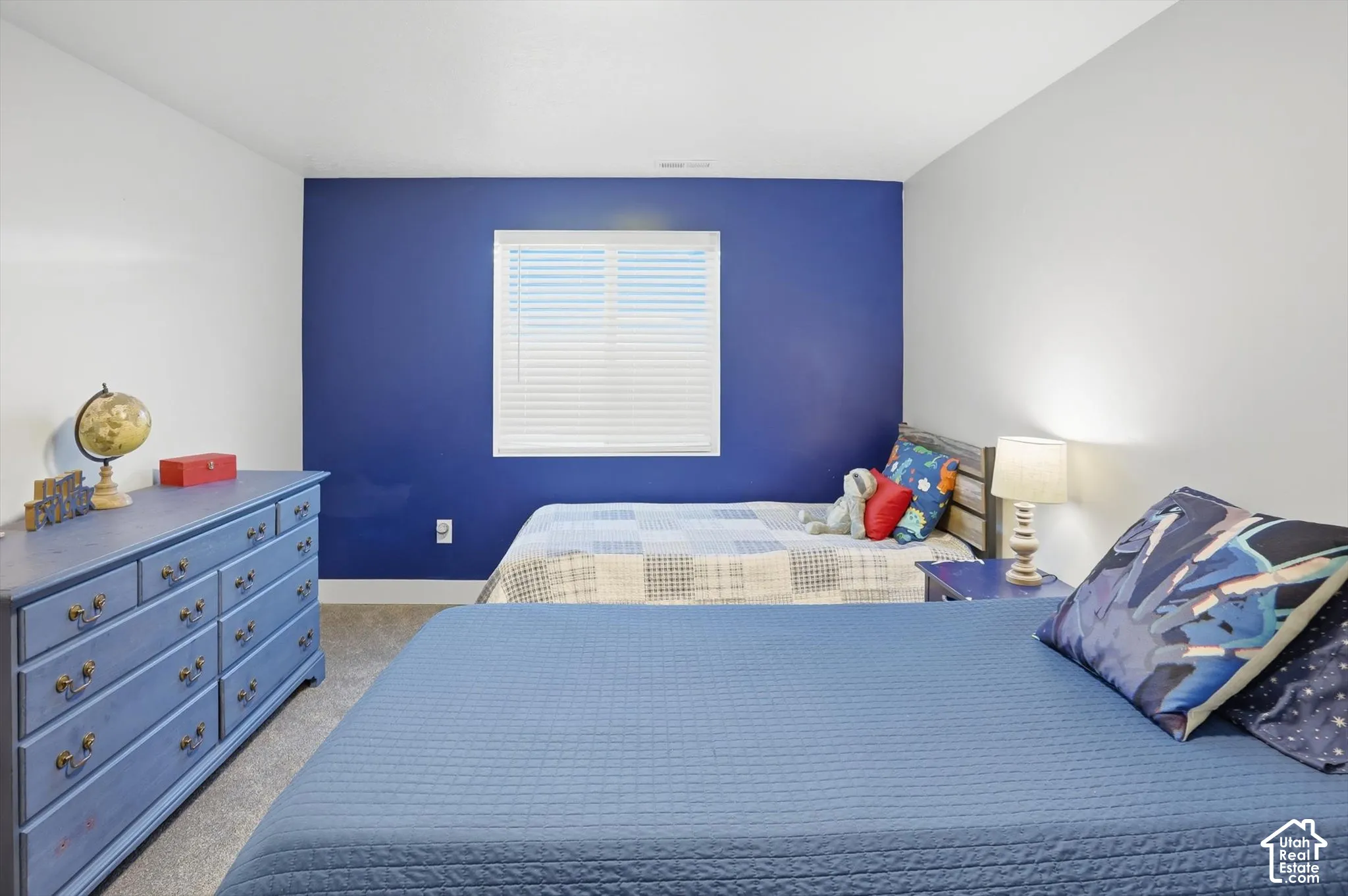 Neutral-toned room featuring a single-wall blue accent, carpeting, and a rectangular window with horizontal blinds