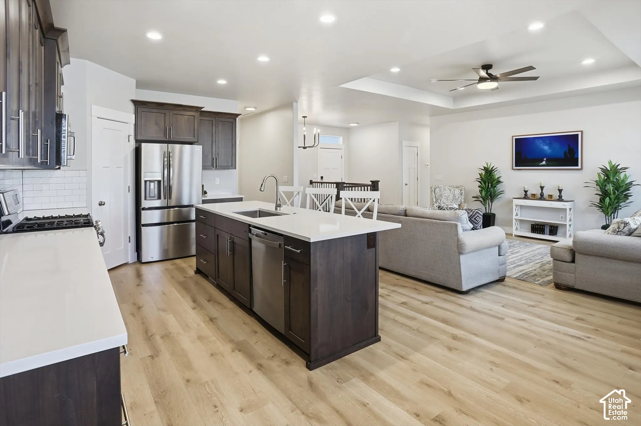 Kitchen featuring dark-stained cabinetry, quartz countertops, a central island with an undermount sink, recessed lighting, and wood-finish flooring
