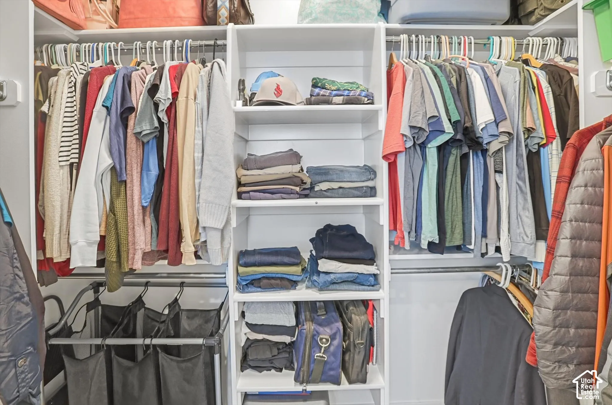 Walk-in closet featuring white built-in shelving, adjustable horizontal storage cubbies, and multiple metal hanging rods