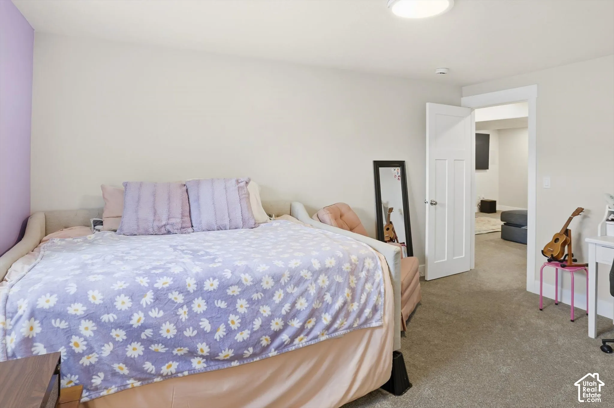 Neutral wall tones, carpeting, and a three-panel interior door with brushed metal hardware
