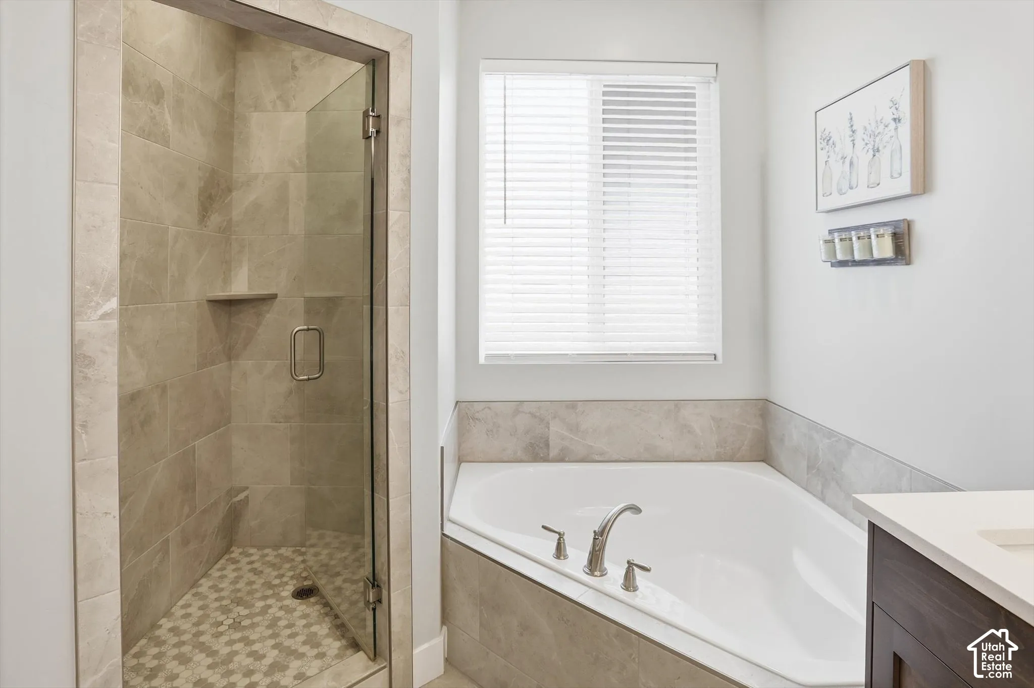 Walk-in shower with tile surround, glass enclosure, and mosaic tile flooring, paired with a white corner soaking tub featuring a tile surround and chrome fixtures