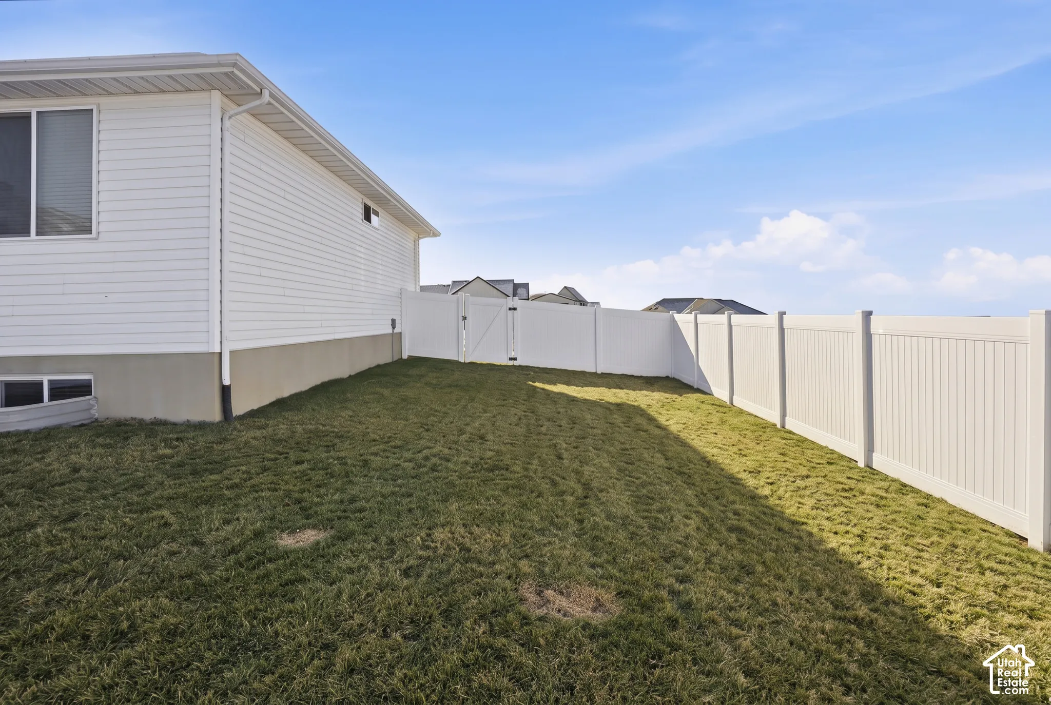 Backyard featuring white vinyl privacy fencing and a gated side entrance
