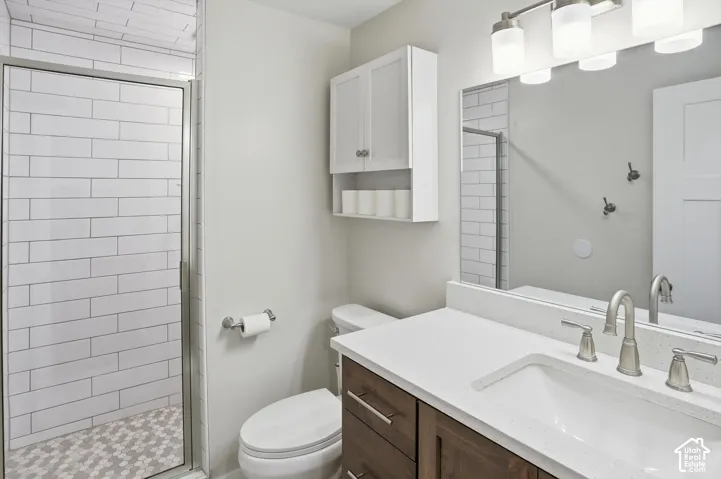 Bathroom featuring a vanity with wood-finish cabinetry and a stone-composite countertop, undermount sink, shower with white subway tile surround and hexagonal floor tile, and a wall-mounted medicine cabinet