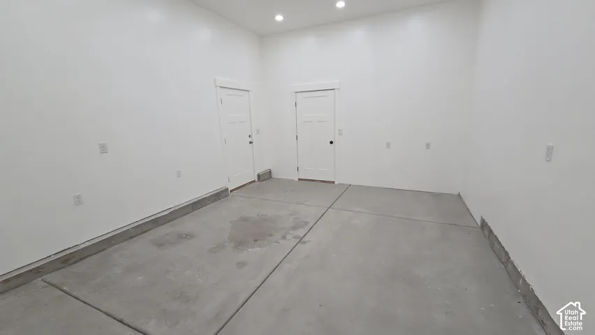 Finished garage interior featuring smooth white walls, high ceilings with recessed lighting, and two solid-core panel doors