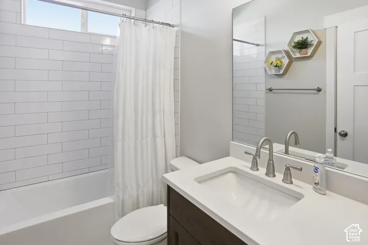 Bathroom featuring white subway tile wall surround, dark-finish vanity cabinet with a light-tone countertop, undermount sink, brushed nickel faucet, and a wall-to-wall mirror