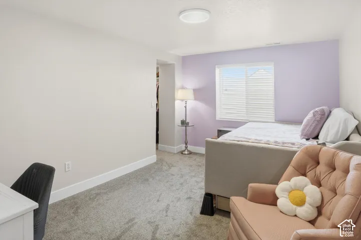 Room featuring neutral carpeting, a dual-tone wall finish, an integrated closet space, and a sliding window with horizontal blinds