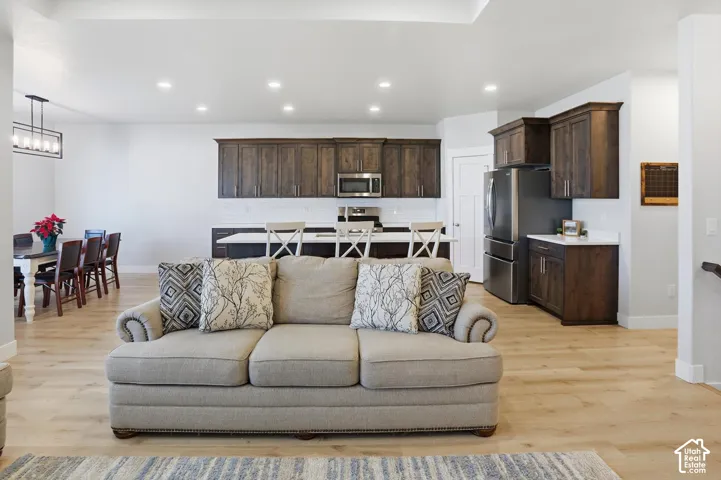 Kitchen featuring dark wood cabinetry, stainless steel appliances, a center island with a stone countertop, recessed lighting, and wood-finish flooring