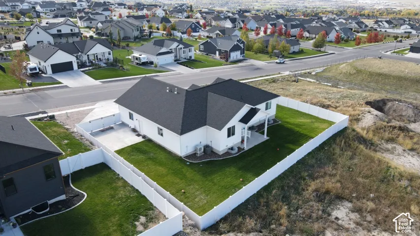 Single-story residence featuring a white exterior, dark asphalt shingle roof, concrete patio, and a fully enclosed vinyl privacy fence surrounding the rear lawn