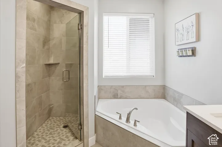 Walk-in shower with tile surround, glass enclosure, and mosaic tile flooring, paired with a white corner soaking tub featuring a tile surround and chrome fixtures
