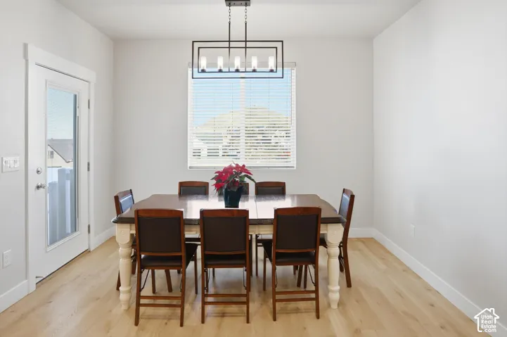 Neutral-toned walls paired with light wood-finish flooring, a contemporary linear five-light chandelier, and a glass-paneled exterior door