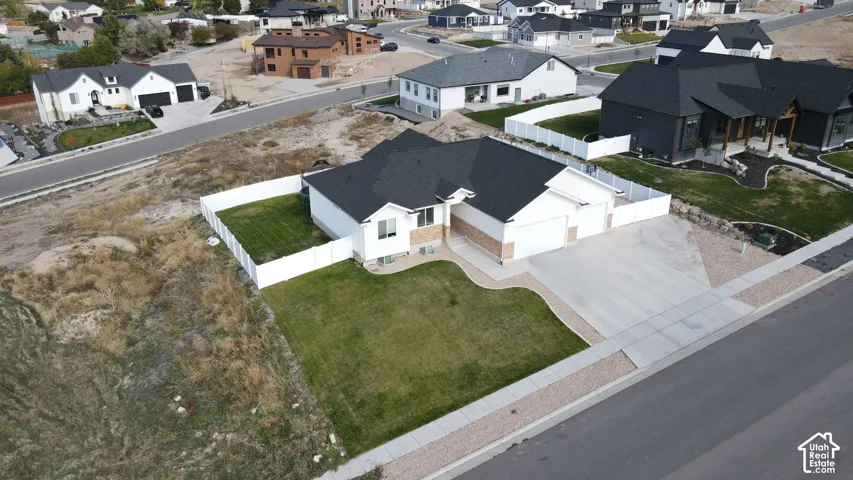 Single-story residence featuring a multi-gable roof, attached three-car garage, white vinyl fencing, and a concrete driveway