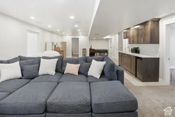 Finished space featuring recessed lighting, wet bar with dark-toned cabinetry, light-toned countertops, and neutral carpeting