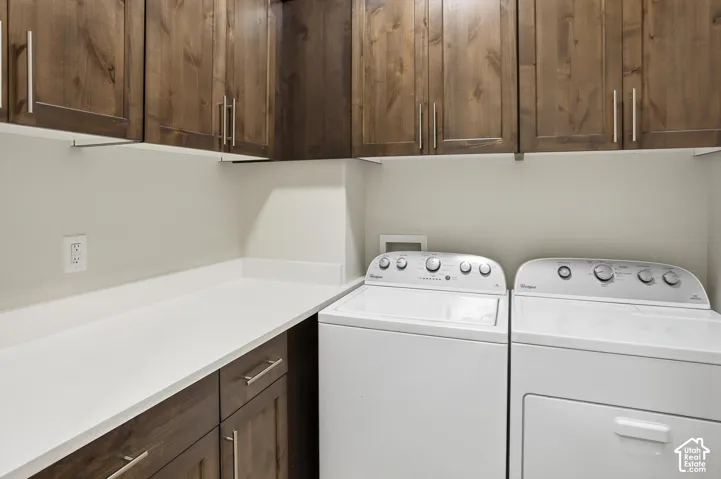Laundry room featuring stained wood cabinetry, a solid-surface countertop, and stainless steel hardware