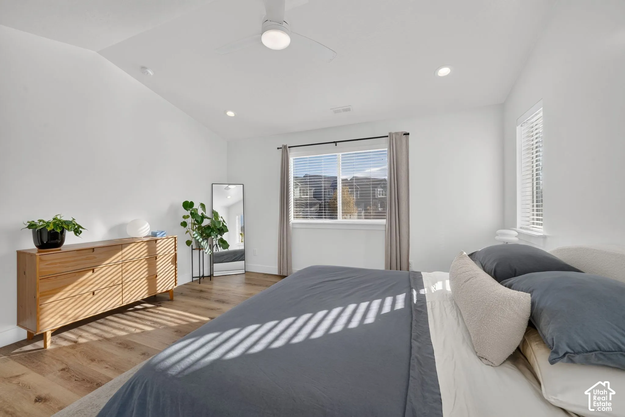 Vaulted ceilings, wood-finish flooring, recessed lighting, and a ceiling fan