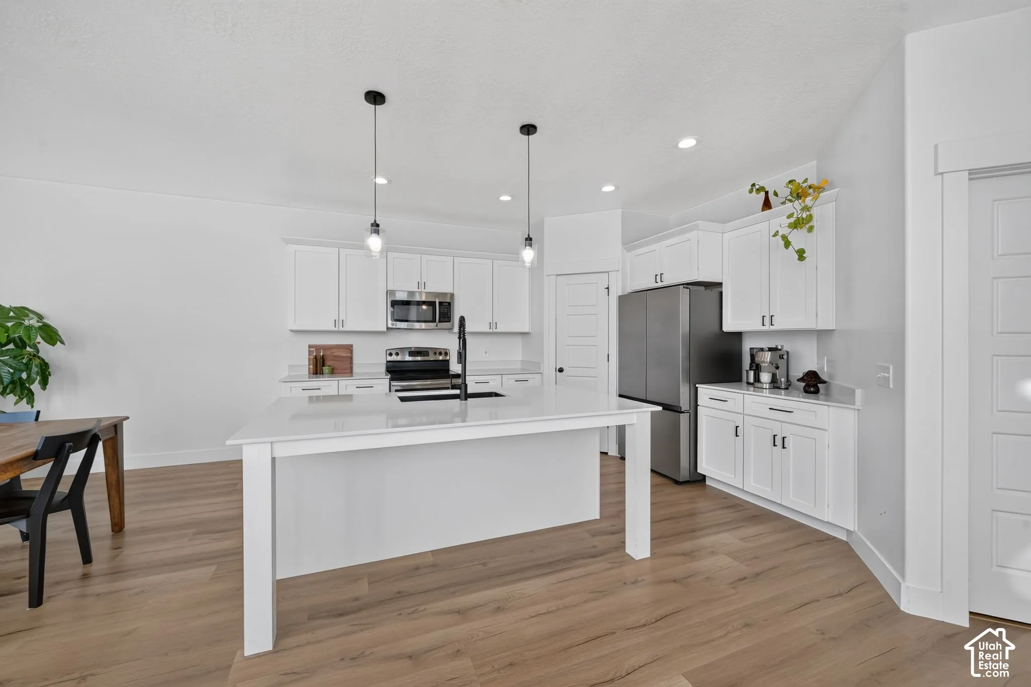 Kitchen featuring white shaker cabinetry, quartz countertops, a central island, recessed lighting, and wood-finish flooring
