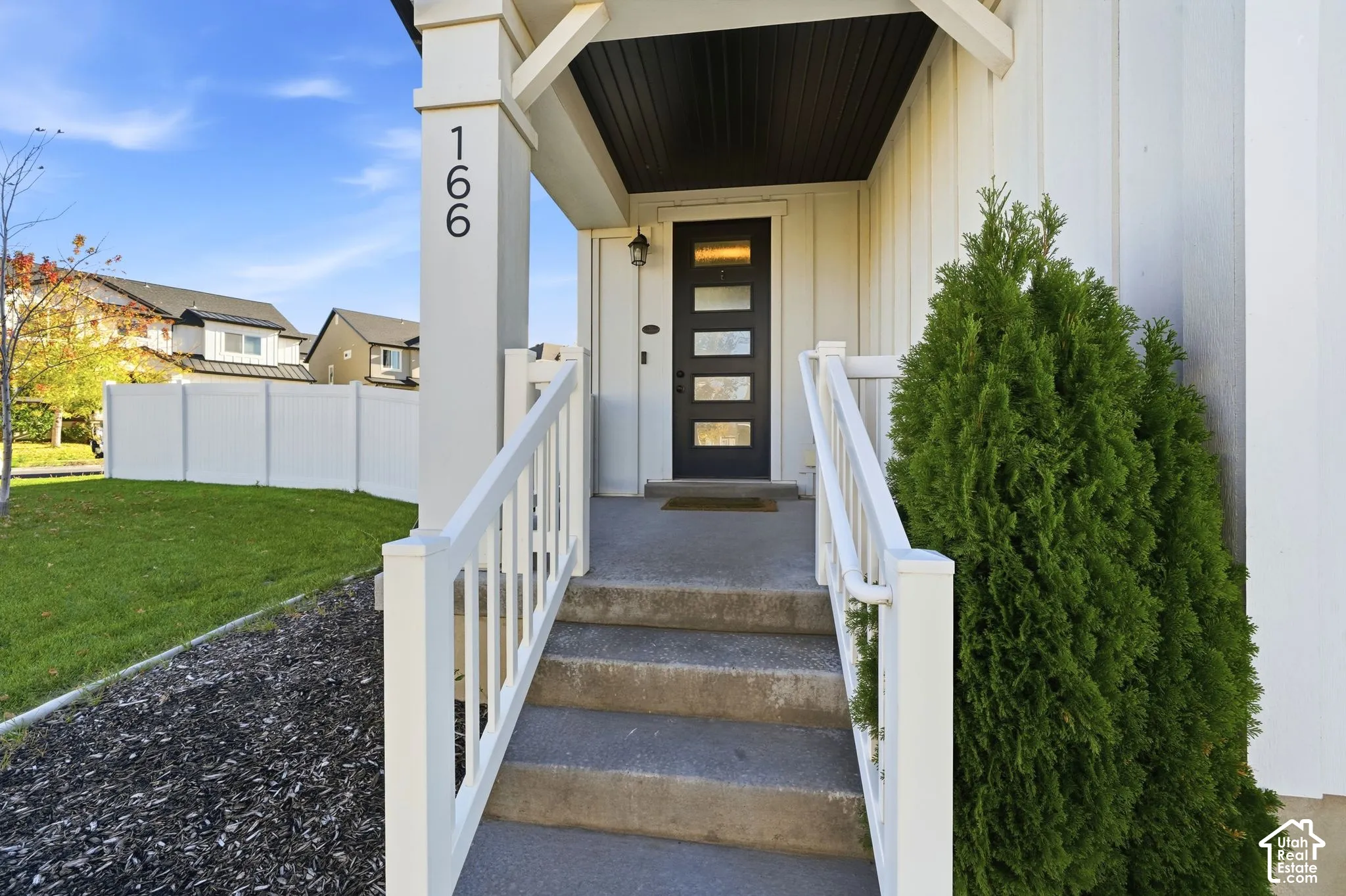 Covered entryway featuring vertical siding, concrete steps with white railing, and a multi-panel door with glass inserts