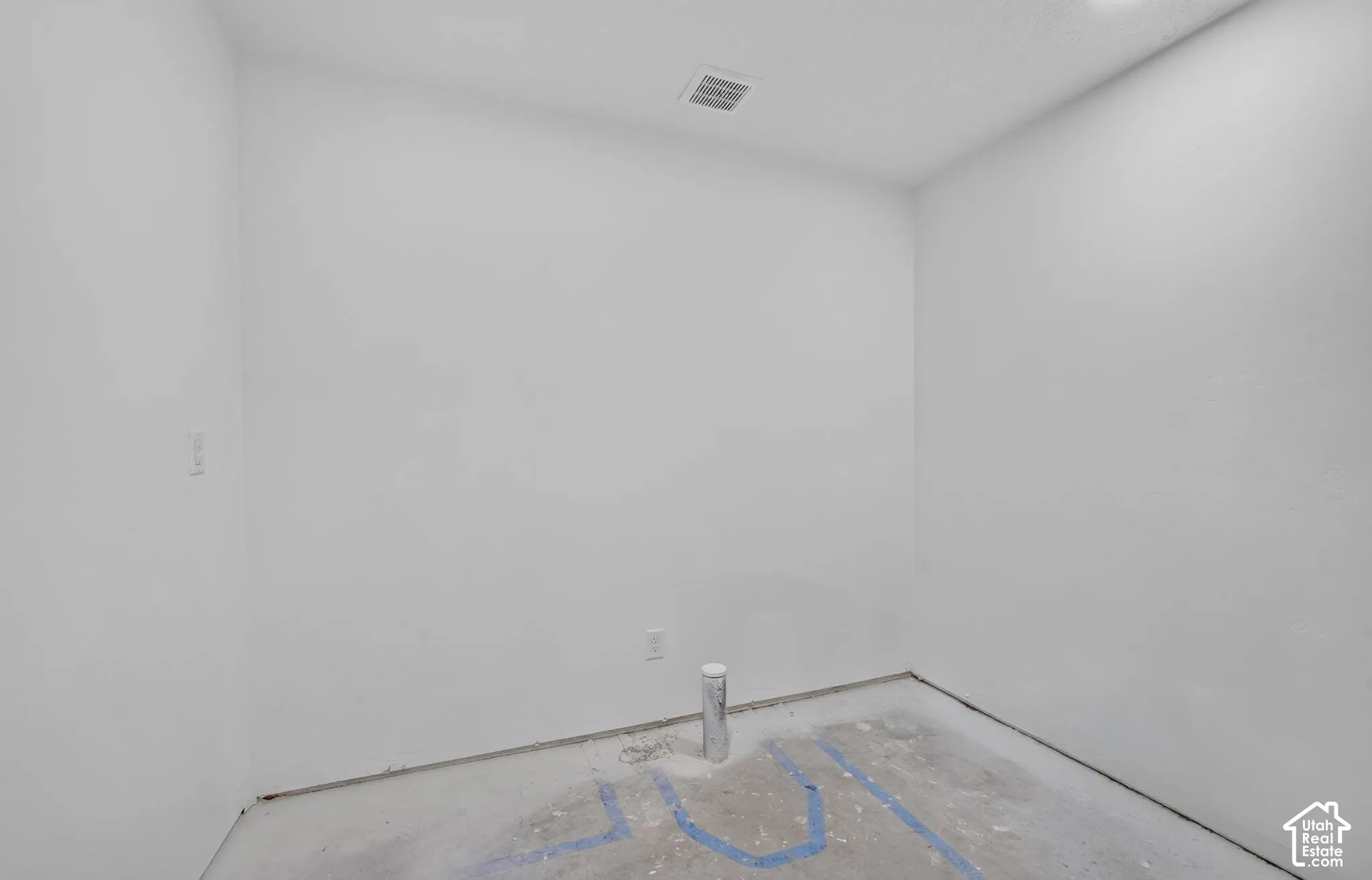 Interior space featuring white walls, concrete flooring, and exposed plumbing infrastructure
