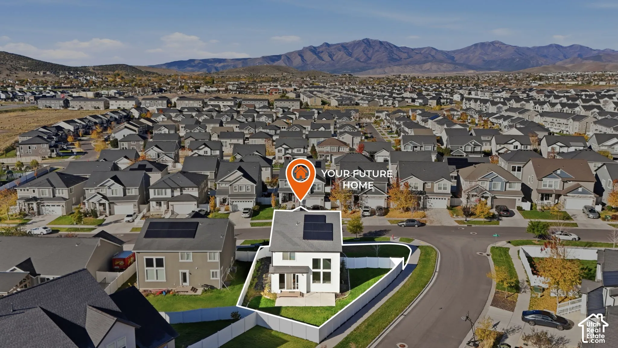 Aerial perspective of a detached residence featuring rooftop solar panels, a fenced backyard, a concrete patio, and a mountain backdrop